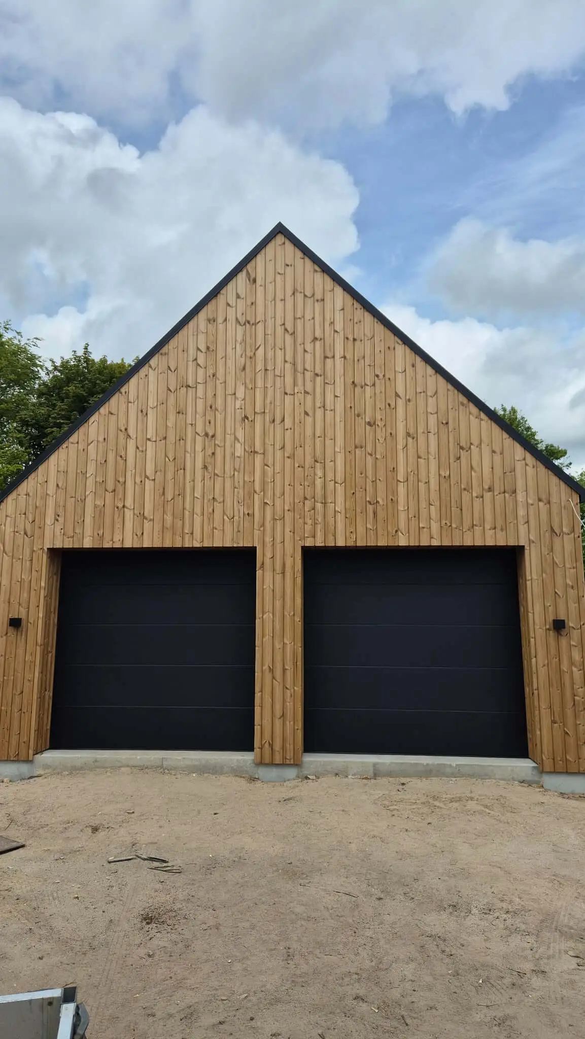 Sorte garageporte på træbeklædt bygning ved indkørsel